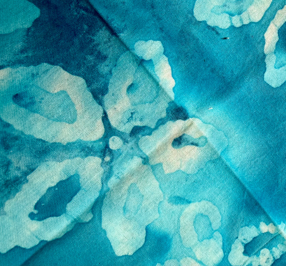 A close-up of a blue and white batik fabric with a watercolor-style floral pattern.